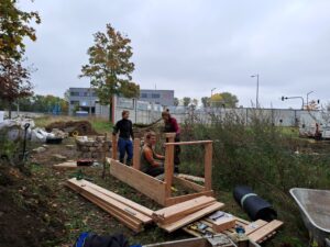 Drei Personen bauen an einem Hochbeet aus Lärchenholz.